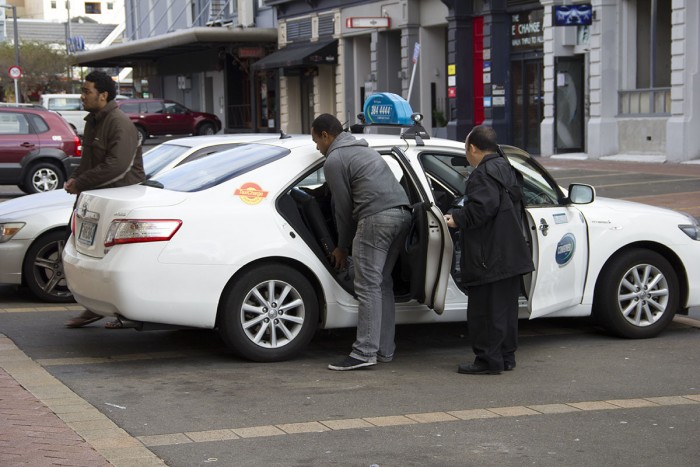 A taxi driver collects a passenger.