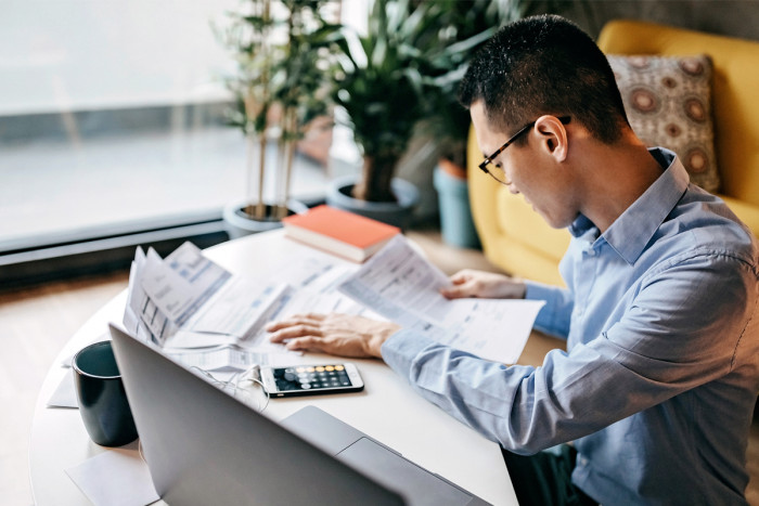 A telecommunications engineer working at a desk that has papers and a smartphone on it