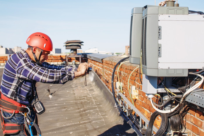 A telecommunications technician examining and photographing telecommunications equipment