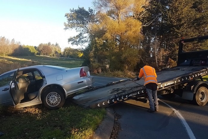 Tow truck driver prepares to move a vehicle from a crash site