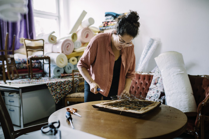 An upholsterer repairs a chair frame