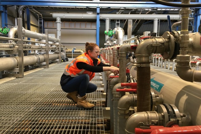 A water treatment operator checks pipes in a water treatment plant