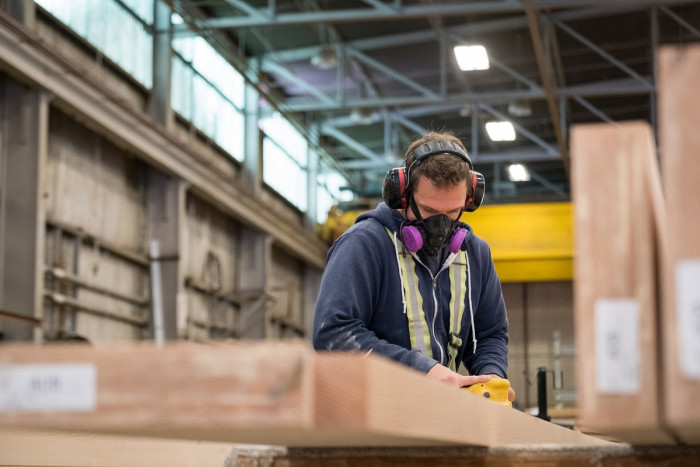 A wood processing worker planes a plank of wood.