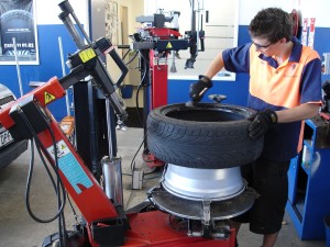 A tyre technician removes a tyre from a wheel rim.