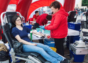 A phlebotomist takes the blood of a woman donor as they sit in a blood donation tent