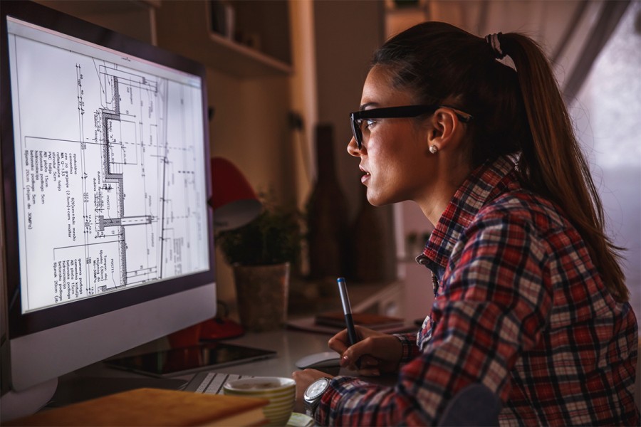 A female architect studies a plan on a monitor
